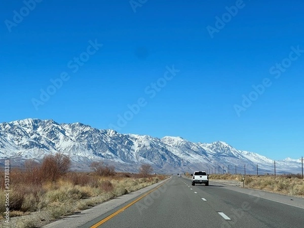 Fototapeta View of road with white pickup truck ahead, driving towards mountains on US Route 395, between Independence and Lone Pine, California