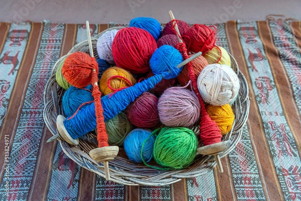 Fototapeta Top view of a basket with alpaca wool yarn balls and spinning spindles in a textile production center in Cusco, Peru.