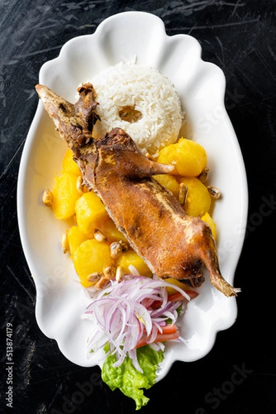 Fototapeta Peruvian food: Roasted guinea pig served with potatoes and rice, traditional in Peru, Ecuador and Bolivia. Top View