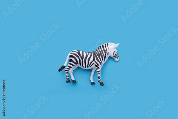 Fototapeta Plastic zebra toy on blue background.