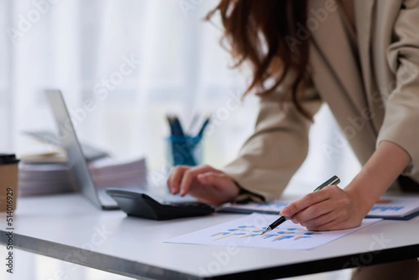Fototapeta Asian businesswoman working on laptop computer and graph planning a strategy in modern office, Asian woman doing analyzing the financial report, business plan investment, finance analysis concept