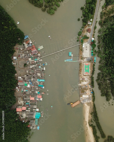 Obraz Top down aerial view of a fishing village with a football field in the mangrove jungle
