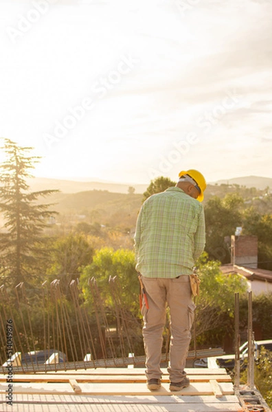 Obraz bricklayers with yellow helmet and protective glasses building on a roof with a sunset - PHOTO SESSION: WORK IN CONSTRUCTION