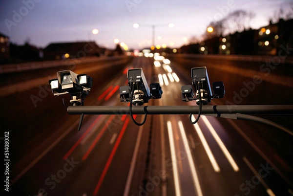Obraz Speed camera monitoring busy traffic road at night. Highway underpass traffics present, long exposure applied lights trail present.