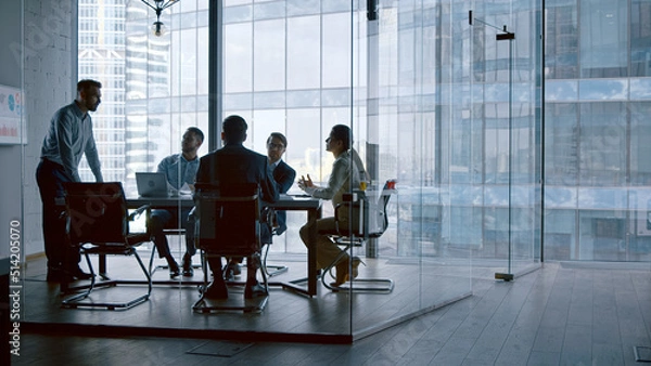 Obraz Business people listening the presenter while sitting at desk