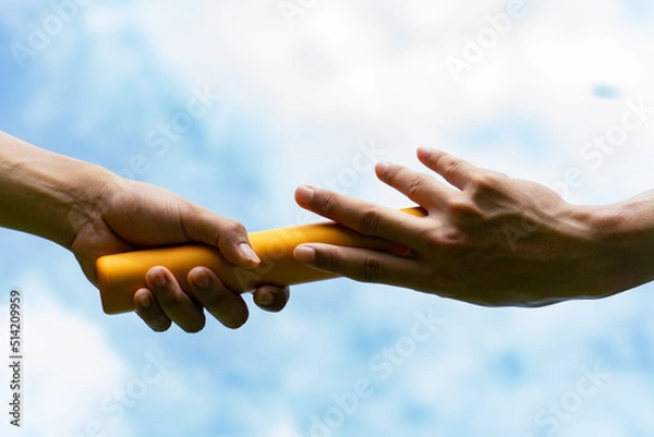 Fototapeta Close up hand set baton from hand to hand on sky background. Business concept for teamwork and team builder.
