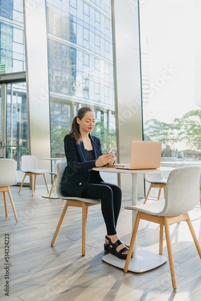 Obraz A female realtor in a blazer is working at the table in the modern lobby