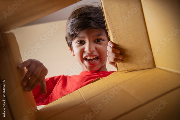 Fototapeta Portrait of boy opening a cardboard box