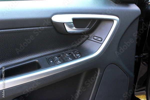 Fototapeta Door handle with windows controls and adjustments in black leather interior. Window switches.