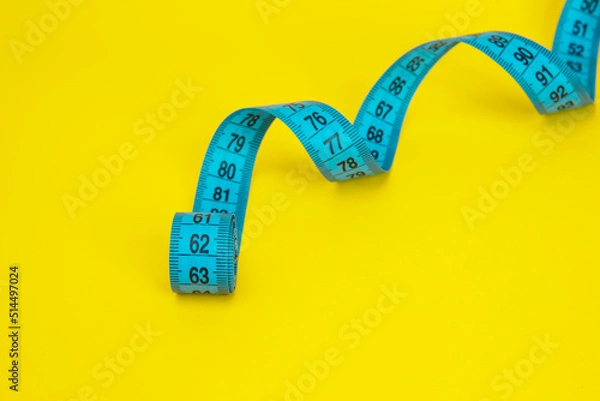 Fototapeta Blue tape measure diet concept on yellow background with copyspace