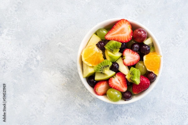 Fototapeta Healthy fresh fruit salad in bowl on gray concrete background. top view. Copy space.