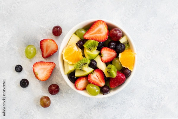 Fototapeta Healthy fresh fruit salad in bowl on gray concrete background. top view. 