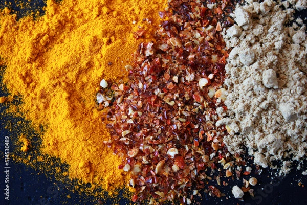 Fototapeta turmeric, chili and galgant powder on a table, different colorful spices on a table as backgroundpices