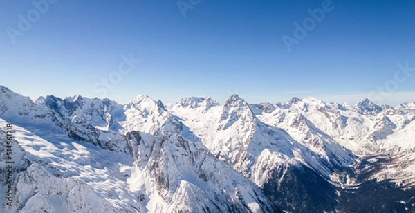 Fototapeta Mountain range covered with snow against a blue sky 