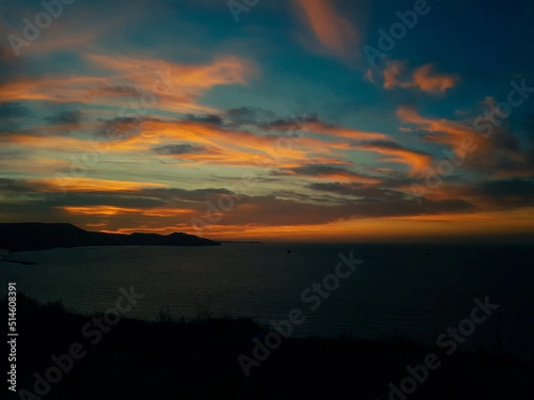 Fototapeta Scenic view of a calm coast during sunset with moutains and jetty in the background, Oran Algeria