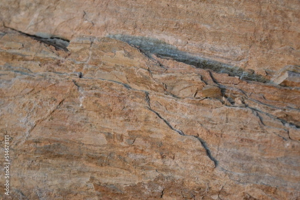 Fototapeta Rough texture of fine natural stone, photographed during golden hour, selective focus