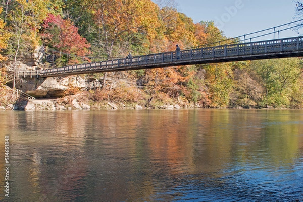 Obraz A hiker crosses a suspension bridge over Sugar Creek in Turkey Run State Park, Indiana.