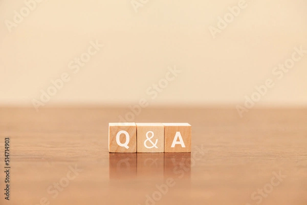 Obraz Q&Aの文字。質問と回答。question and answer。3つの木製ブロックに書かれている。白い文字。木製テーブルと白い壁紙の背景。