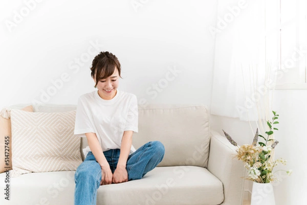 Fototapeta 家のソファに座る笑顔の日本人女性（うつむく・照れる）
