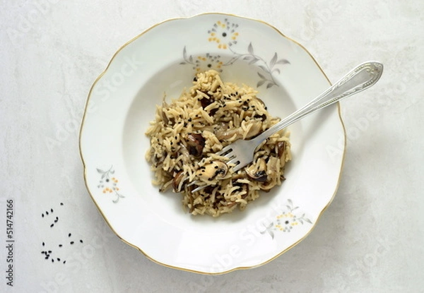 Fototapeta Basmati rice with brown mushrooms and sesame seeds on a gray stone background, top view, copy space