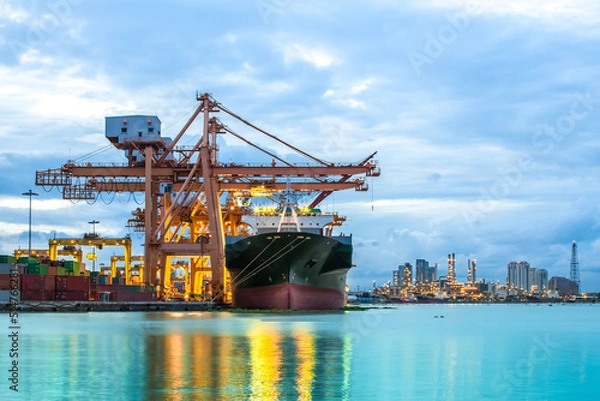 Fototapeta Industrial Container Cargo freight ship with working crane bridge in shipyard at dusk for Logistic Import Export background