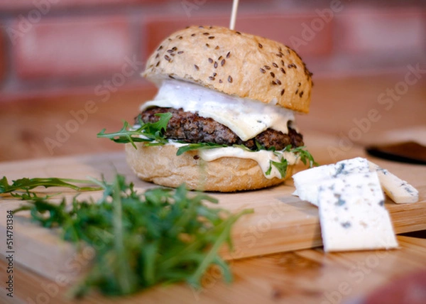 Obraz Burger w artystycznej kompozycji z frytkami i batatami oraz cebulą pieczarkami. Burgerownia - zdjęcie świeżego, apetycznego burgera