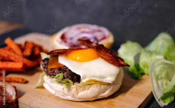 Obraz Burger w artystycznej kompozycji z frytkami i batatami oraz cebulą pieczarkami. Burgerownia - zdjęcie świeżego, apetycznego burgera