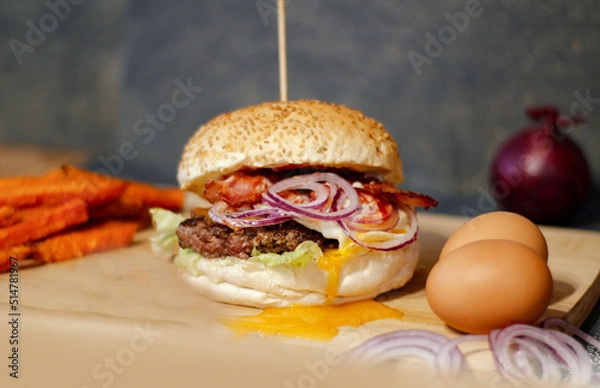 Obraz Burger w artystycznej kompozycji z frytkami i batatami oraz cebulą pieczarkami. Burgerownia - zdjęcie świeżego, apetycznego burgera