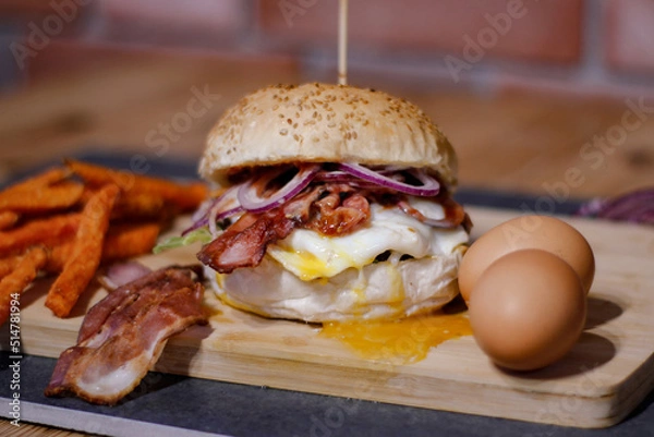 Obraz Burger w artystycznej kompozycji z frytkami i batatami oraz cebulą pieczarkami. Burgerownia - zdjęcie świeżego, apetycznego burgera