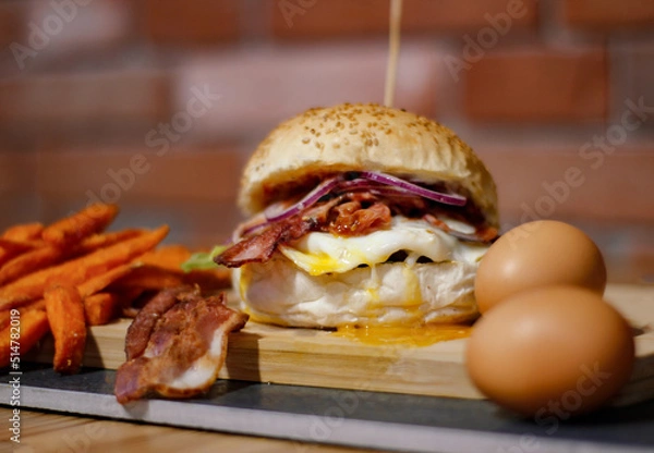 Obraz Burger w artystycznej kompozycji z frytkami i batatami oraz cebulą pieczarkami. Burgerownia - zdjęcie świeżego, apetycznego burgera