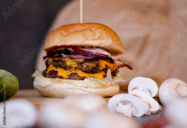 Obraz Burger w artystycznej kompozycji z frytkami i batatami oraz cebulą pieczarkami. Burgerownia - zdjęcie świeżego, apetycznego burgera