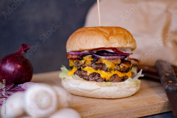 Obraz Burger w artystycznej kompozycji z frytkami i batatami oraz cebulą pieczarkami. Burgerownia - zdjęcie świeżego, apetycznego burgera