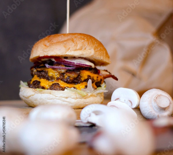 Obraz Burger w artystycznej kompozycji z frytkami i batatami oraz cebulą pieczarkami. Burgerownia - zdjęcie świeżego, apetycznego burgera