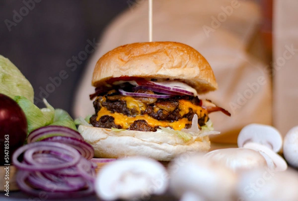 Obraz Burger w artystycznej kompozycji z frytkami i batatami oraz cebulą pieczarkami. Burgerownia - zdjęcie świeżego, apetycznego burgera