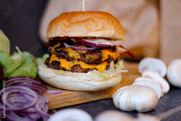 Obraz Burger w artystycznej kompozycji z frytkami i batatami oraz cebulą pieczarkami. Burgerownia - zdjęcie świeżego, apetycznego burgera