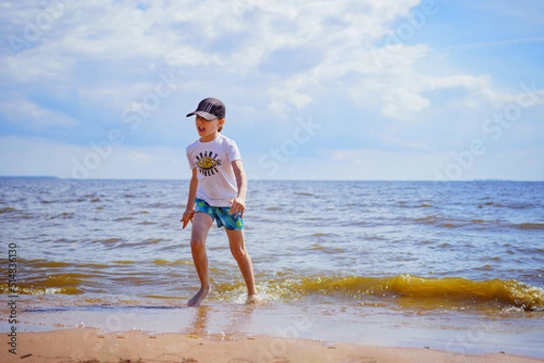 Obraz Happy little boy is running in the sea on sunny summer day. Childhood concept