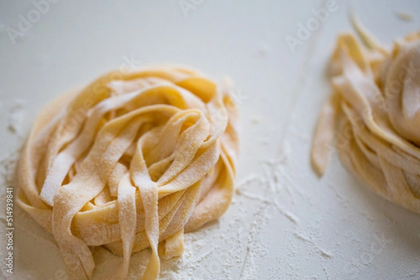 Obraz Homemade tagliatelle pasta folded in the shape of a nest. Home cooking of traditional Italian pasta.