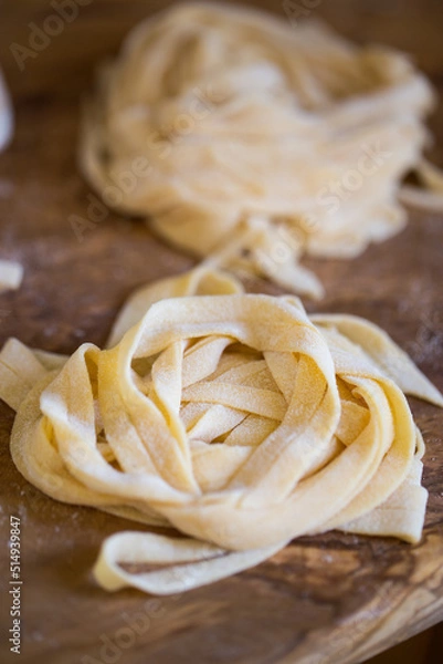 Obraz Homemade tagliatelle pasta folded in the shape of a nest. Home cooking of traditional Italian pasta.