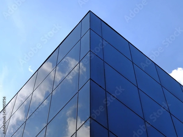 Fototapeta Modern glass building against the blue sky. Bottom view of modern skyscraper in business district