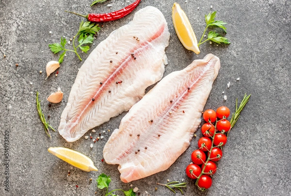 Fototapeta Fresh raw white fish fillet Pangasius with spices and lemon on a stone background.