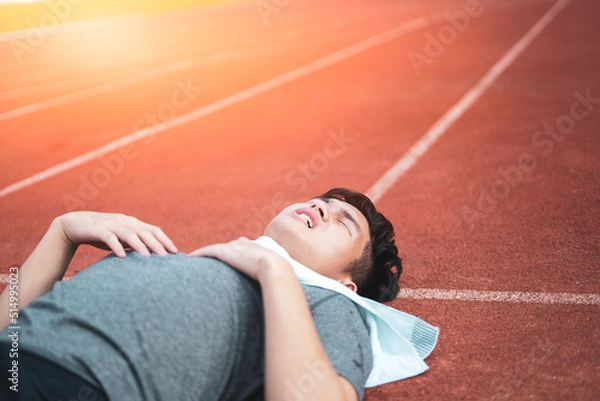 Fototapeta Exhausted man resting after jogging in the stadium during day.