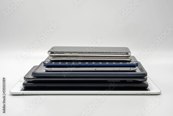 Fototapeta Stack of cell phones and pads on white background