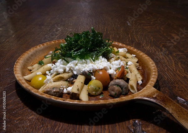Fototapeta Fried noodles with mushrooms, tomato and feta cheese on a brown plate for menu in the restaurant or cafe copy space