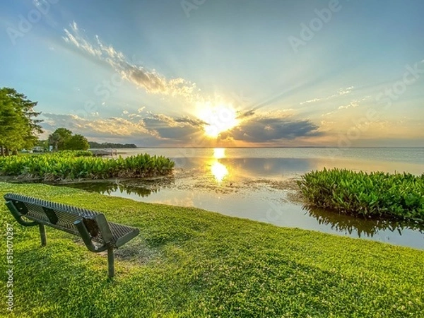 Fototapeta Park bench with view of brilliant sunset at Newton Park on Lake Apopka at Winter Garden, Florida