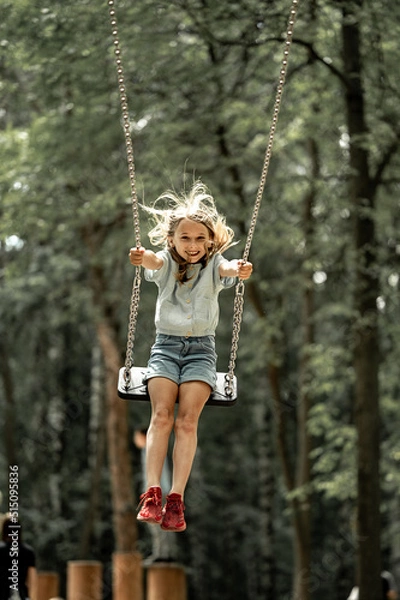 Obraz a girl walks in the park, swings on a swing