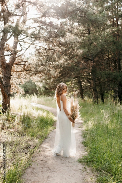 Fototapeta happy bride girl in a white light dress with a bouquet of dried flowers