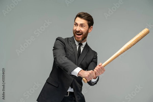 Fototapeta Waist up portrait view of the caucasian businessman swings with a baseball bat standing over grey background. Occupation concept