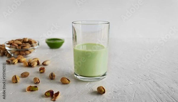 Fototapeta Pistachio milk in the glass and pistachio paste  on the white background. This milk is a great source of antioxidants, phytosterols, and heart healthy fats
