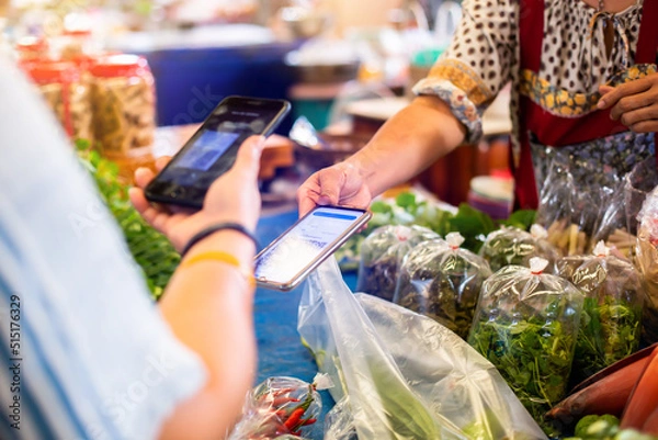 Fototapeta Selective focus to customer hand using smart phone to scan Qr code payment tag  with blurry vegetable in fresh market to accepted generate digital pay without money. Qr code payment concept.