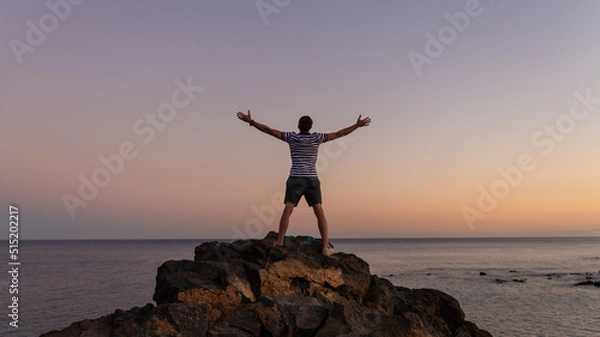 Fototapeta Carriages man standing on rock in win pose in sunset.